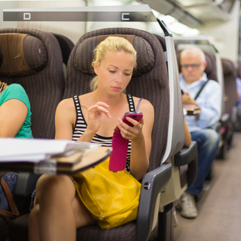 junge Frau nutzt als Fahrgast im Zug das Smartphone