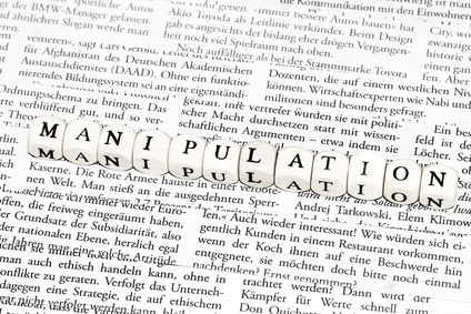 Das Wort "Manipulation" zusammengesetzt aus Buchstabenwürfeln vor gedrucktem Text