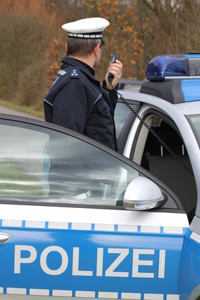 Polizist mit Funkgerät am Fahrzeug