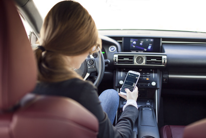 Frau nutzt Smartphone am Steuer eines Autos