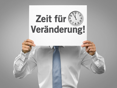 Ein Geschäftsmann hält ein Plakat "Zeit für Veränderung" vor seinem Kopf